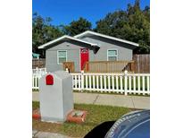 Charming single-story home featuring a red front door, a spacious porch and a white picket fence at 910 Seminole St, Clearwater, FL 33755