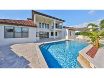 Back exterior featuring a private pool with a waterfall feature, travertine tile deck, and covered patio at 912 Symphony Beach Ln, Apollo Beach, FL 33572