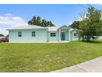 Inviting single-story home with light-blue paint, white metal roof, and lush green lawn at 9321 Regatta Cir, Spring Hill, FL 34606