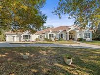 Charming single-story home featuring a red tile roof, lush landscaping, and a circular driveway at 1011 Riverside Ridge Rd, Tarpon Springs, FL 34688