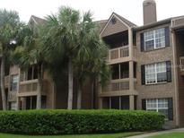 Charming condo building featuring a brick facade, multiple balconies, and lush landscaping at 10200 Gandy N Blvd # 209, St Petersburg, FL 33702