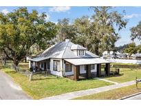 Charming home with a unique roof, inviting front porch, and mature trees at 14329 14Th St, Dade City, FL 33523