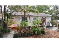 Exterior view of backyard with greenery and partially covered deck and home in need of repairs at 1207 Pine Nw Ave, Largo, FL 33770