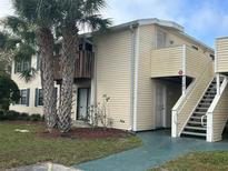 Exterior view of two-story condominium with palm trees, stairs, and a balcony at 121 Loblolly Ct # H, Oldsmar, FL 34677