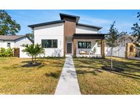 Modern two-story home featuring a manicured lawn, minimalist landscaping and a covered porch with lounge seating at 3721 6Th N Ave, St Petersburg, FL 33713