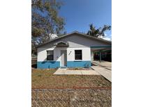 Charming home featuring a unique blue and white exterior, covered carport, and fenced front yard at 5511 N 32Nd St, Tampa, FL 33610