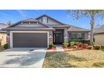 Charming single-story home with a two-car garage, stone accents, manicured lawn, and a welcoming entryway at 12222 Legacy Bright St, Riverview, FL 33578
