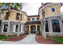 Stunning home featuring a stone facade, arched entry, and a meticulously landscaped front yard with mature palm trees at 2171 Portofino Place # 27-2725, Palm Harbor, FL 34682