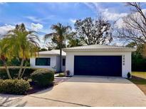 Charming single-story home featuring a metal roof, manicured landscaping, and an attached two-car garage at 2488 Orangepointe Ave, Palm Harbor, FL 34683