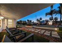 Inviting front porch with stylish seating and modern landscape design with palm trees at sunset at 741 Mandalay Ave, Clearwater Beach, FL 33767