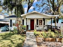 Charming single-story home with a red front door, a cozy front porch, and a well-manicured lawn at 1210 E Sligh Ave, Tampa, FL 33604