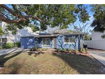 Charming blue home featuring a well-manicured lawn and mature landscaping at 1545 Pasadena Dr, Dunedin, FL 34698