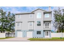 Three-story home with a gray siding, white trim, a two-car garage, and a well-manicured lawn at 320 Georgia Ave, Crystal Beach, FL 34681