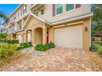 Charming townhome exterior with a one-car garage, brick paved driveway, and landscaped front yard at 876 Callista Cay Loop, Tarpon Springs, FL 34689