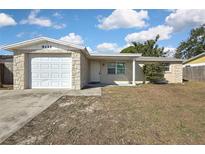 Charming single-story home with stone accents, an attached garage, and a well-lit front entrance at 9111 Sterling Ln, Port Richey, FL 34668