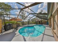 Screened-in pool area with blue tiling, sun umbrella, dining set, and an inground jacuzzi at 1401 Ventana Dr, Sun City Center, FL 33573