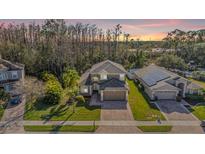 Beautiful home exterior with mature trees, manicured lawn, brick driveway, and a two-car garage at 212 Arbor Woods Cir, Oldsmar, FL 34677