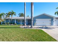 Charming single-story home with manicured lawn, mature palm trees, and a two-car garage at 230 S Julia Cir, St Pete Beach, FL 33706