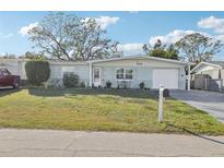 Charming home featuring a well-maintained front lawn and a cozy outdoor seating area at 2419 Palmwood Dr, Holiday, FL 34690