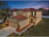 Two-story home with a red tile roof, neutral stucco, stone accents, and a two-car garage at 19609 Timberbluff Dr, Land O Lakes, FL 34638