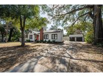 Charming single-story home with a brick chimney, an orange front door, and a detached two-car garage at 1209 E Idlewild Ave, Tampa, FL 33604