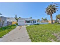 Charming single-story home featuring a well-maintained front yard and a mature palm tree under a clear blue sky at 15548 1St E St, Redington Beach, FL 33708