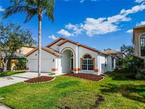 Charming single-story home featuring a well-manicured lawn, a two-car garage, and eye-catching white and orange trim at 1609 Shady Oaks Dr, Oldsmar, FL 34677