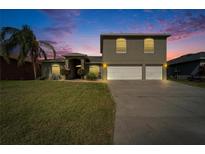 Charming two-story home with lush front yard and three car garage under beautiful sunset sky at 3822 Salida Delsol Dr, Sun City Center, FL 33573