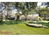 Stunning single-story home boasts lush landscaping, a circular driveway, and an inviting columned entryway at 6222 Kingbird Manor Dr, Lithia, FL 33547