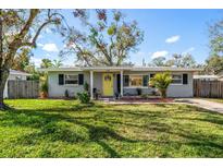 Charming one-story home with a well-maintained lawn, mature trees, and a welcoming yellow front door at 1718 Evans Dr, Clearwater, FL 33759