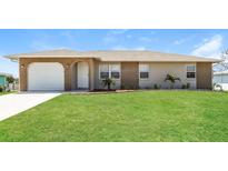Charming single-story home featuring a well-maintained lawn, brick accents, and an attached garage at 28 Caddy Rd, Rotonda West, FL 33947