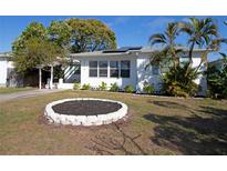 Charming white home featuring lush landscaping, solar panels, and a well-maintained front yard at 4415 4Th S Ave, St Petersburg, FL 33711