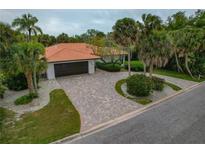 Stunning single-story home with a tile roof, meticulously landscaped grounds, and a long, winding brick driveway at 710 Treasure Boat Way, Sarasota, FL 34242