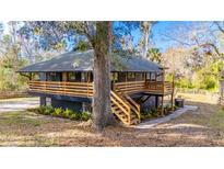 Charming raised home with a wooden deck, staircase, mature trees, and landscaped yard at 8204 Stoner Rd, Riverview, FL 33569