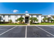 Exterior view of condo building with parking, tropical trees, and well-maintained landscaping at 129 W Cypress Ct, Oldsmar, FL 34677