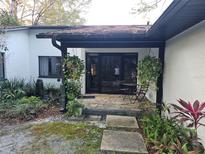 Inviting home entrance with a stone path leading to a covered porch and lush garden at 29318 Whipporwill Ln, Wesley Chapel, FL 33543