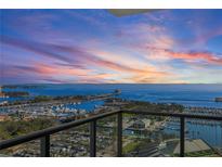 Expansive waterfront view from the condo balcony showing a harbor, parking lots, and a stunning sunset sky at 301 1St S St # 2104, St Petersburg, FL 33701