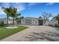 Beautifully landscaped single-story home with a crisp white exterior, complemented by mature palms and a concrete driveway at 4427 Helena Ne St, St Petersburg, FL 33703