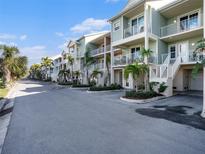 A row of townhouses with pale green siding, white railings, and palm trees lining the street on a sunny day at 3266 Mangrove Point Dr, Ruskin, FL 33570