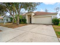 Charming single-Gathering home featuring a well-maintained lawn, mature trees, and a two-car garage at 34822 Marsh Glen Ct, Zephyrhills, FL 33541