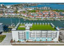 Aerial view of waterfront community, showcasing building, marina, and water at 400 150Th Ave # 302, Madeira Beach, FL 33708