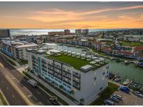 Aerial view of modern building near waterfront with parking and a rooftop terrace at 400 150Th Ave # 301, Madeira Beach, FL 33708