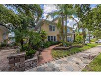 Charming yellow house with brick walkway, lush landscaping, and a spacious front yard at 635 Bay Ne St, St Petersburg, FL 33701