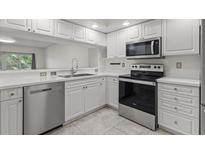 Well-lit kitchen featuring stainless steel appliances, white cabinets, and white countertops at 960 Starkey Rd # 5203, Largo, FL 33771