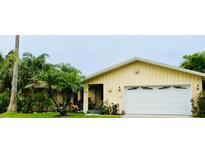 Cute yellow house with white garage door and lush landscaping at 1964 Arvis E Cir, Clearwater, FL 33764