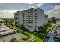 Aerial view of waterfront condo building with tennis courts, pool, and boat slips at 660 Island Way # 301, Clearwater Beach, FL 33767