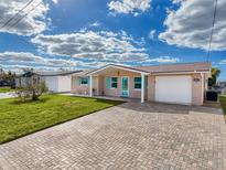 Cute bungalow with a brick driveway, landscaped lawn, and a two-car garage at 12637 2Nd Isle, Hudson, FL 34667