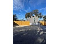 Single-wide manufactured home with wood fence and gravel driveway at 1925 Patriot Ln, Holiday, FL 34690