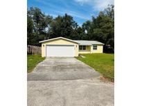 Cute yellow house with a white garage door and a well-maintained lawn at 27173 Simona Ave, Brooksville, FL 34602