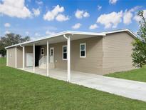 Tan single-story home with covered porch and carport, showcasing a well-maintained lawn at 14287 Rialto Ave, Brooksville, FL 34613